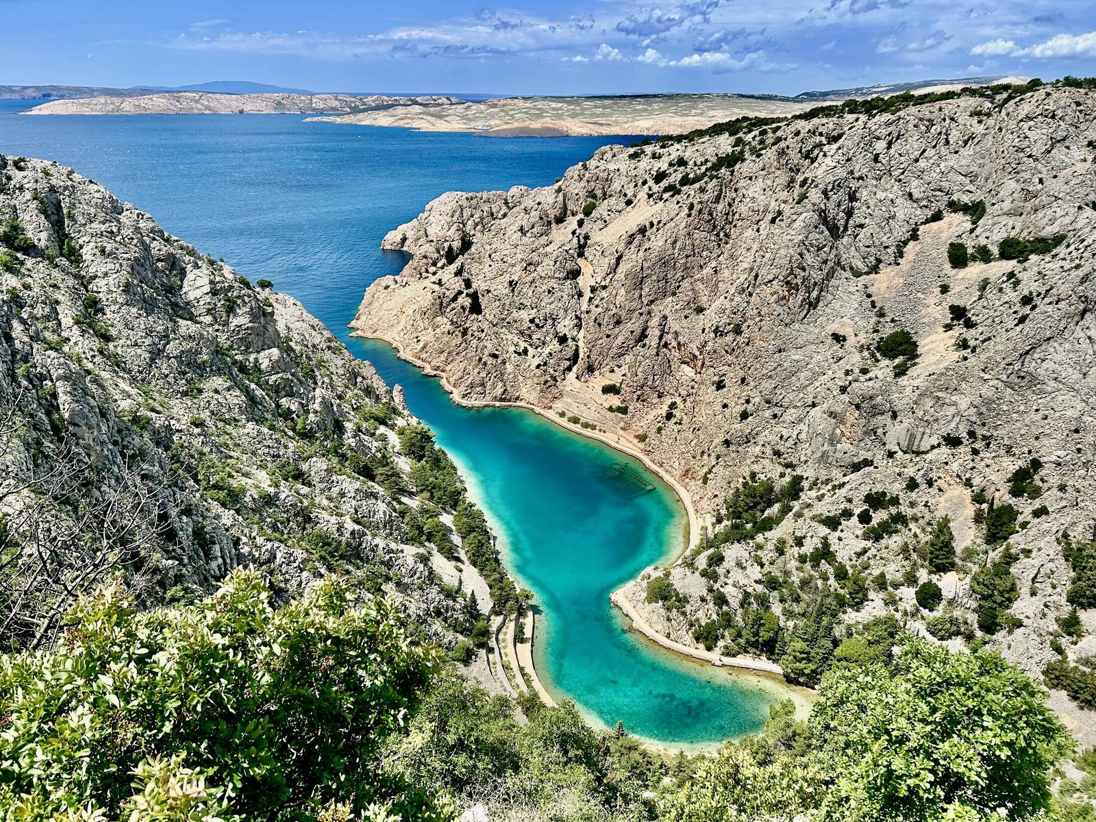 Pogled odozgo na tirkizno more, vapnenačke padine i obalnu stazu Zavratnice